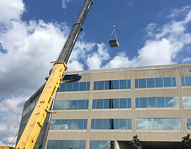 A Crane Lowering a Box on Top of a Building