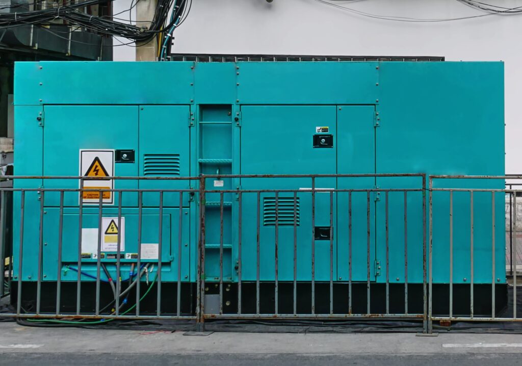 Teal industrial generator behind metal safety railing