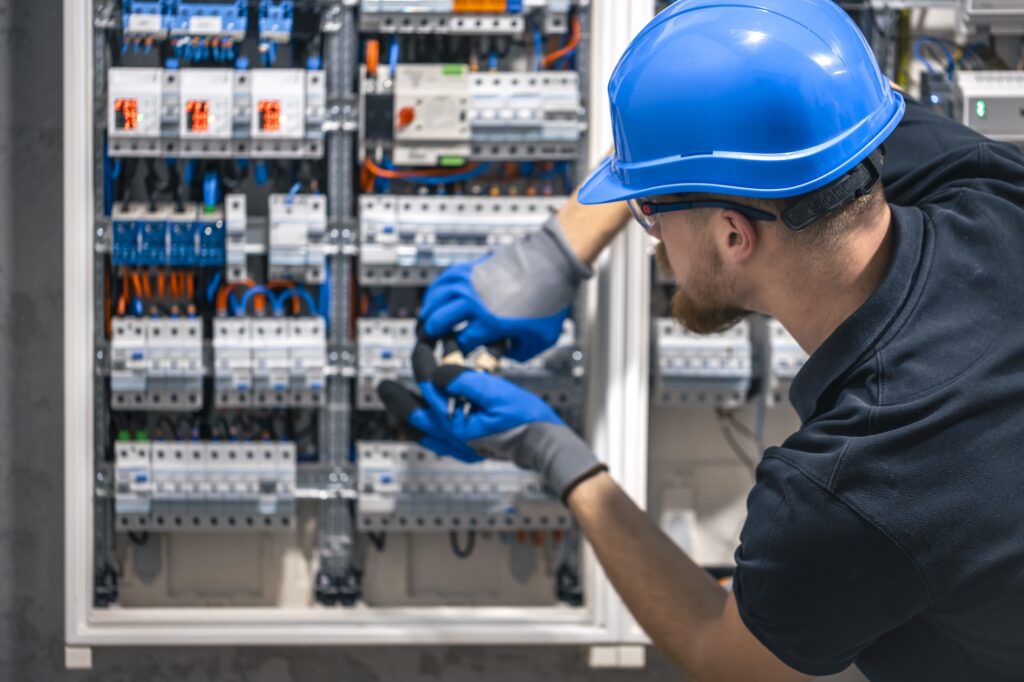 Electrician working on open electrical control panel