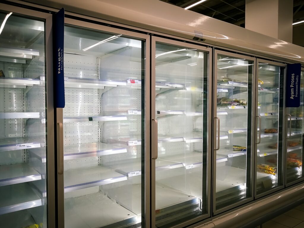 Empty supermarket freezer doors with sparse items